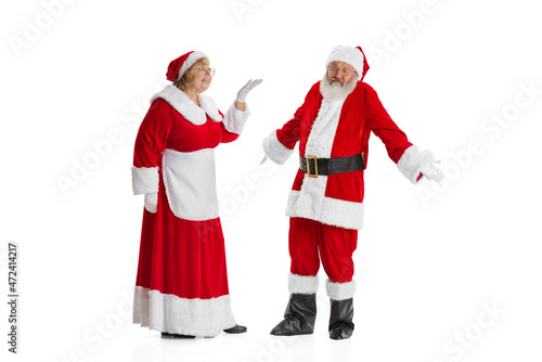 Two people, elder man and woman, Santa Claus and missis Claus in traditional New Year costume talking isolated on white background.