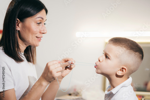 Woman speech therapist helps a boy correct the violation of his speech