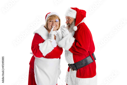 Happy smiling old man in Santa Claus costume and cute woman, missis Claus keeping secrets isolated on white background.