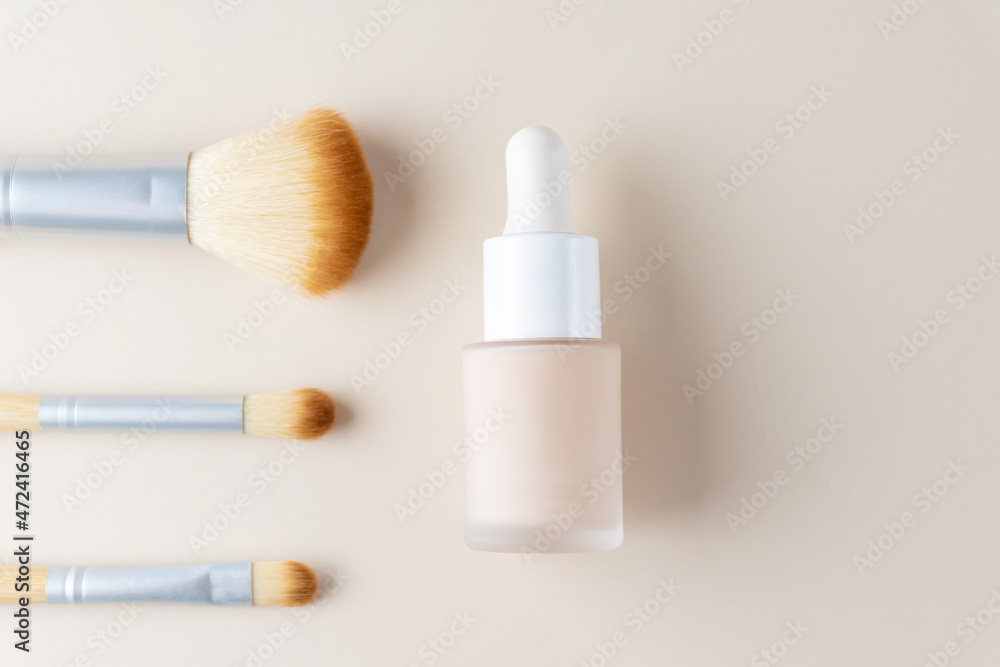 Set of makeup brushes for skin tone correction with a bottle of beige fluid foundation, Makeup foundation background, Fluid foundation base for nude skin with copy space Set of makeup brushes for skin tone correction with a bottle of beige fluid foundation, Makeup foundation background, Fluid foundation base for nude skin with copy space