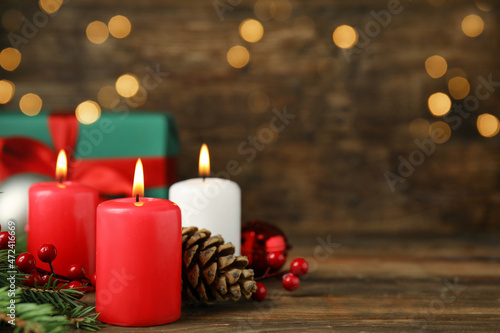 Burning candles  gift box and Christmas decor on wooden table  bokeh effect. Space for text