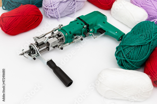 Tufting gun and skeins of yarn of various colors on white background. Cut and pile gun. Carpet hand tufting machine