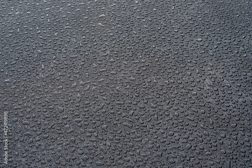 Dark background with large drops of water on fresh asphalt. Road surface wet from rain. Black sad backdrop