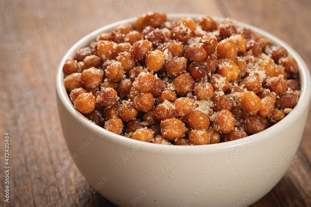 Close up bowl of roasted chickpeas with grated cheese on wooden table Close up bowl of roasted chickpeas with grated cheese on wooden table