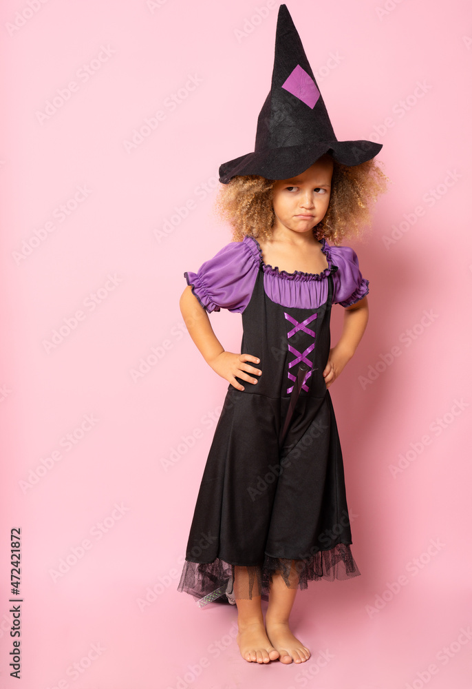 Little girl posing in a witch costume isolated over pink background. Little girl posing in a witch costume isolated over pink background.