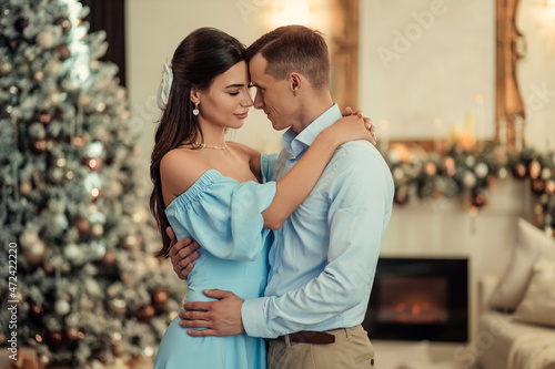 happy couple husband and wife at home in living room near christmas tree