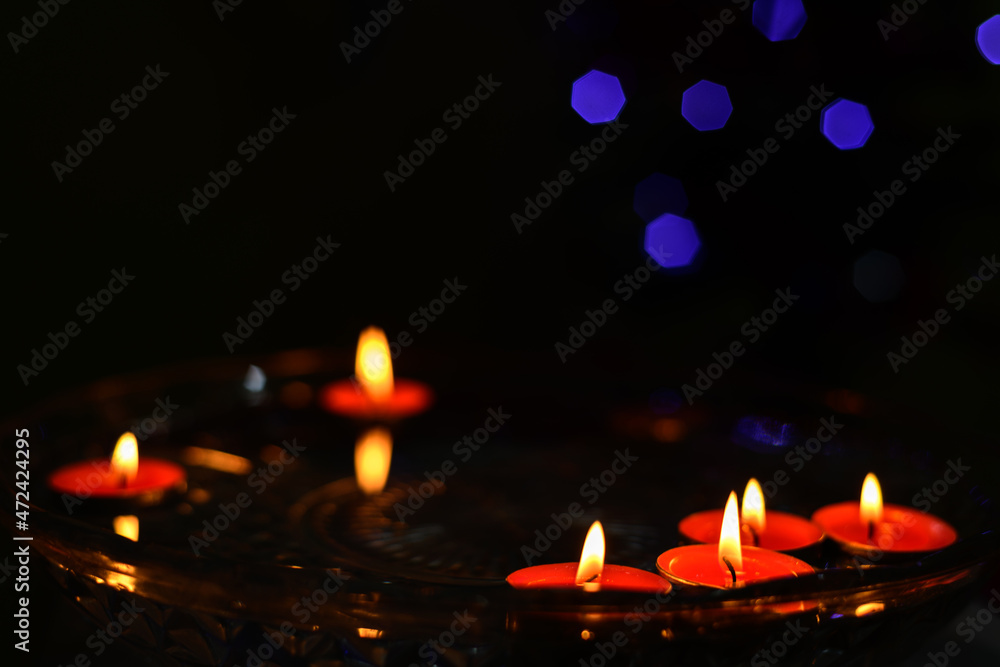 Floating candles on the water in the dark, orange cylindrical wax candles burning close up. Floating candles on the water in the dark, orange cylindrical wax candles burning close up.