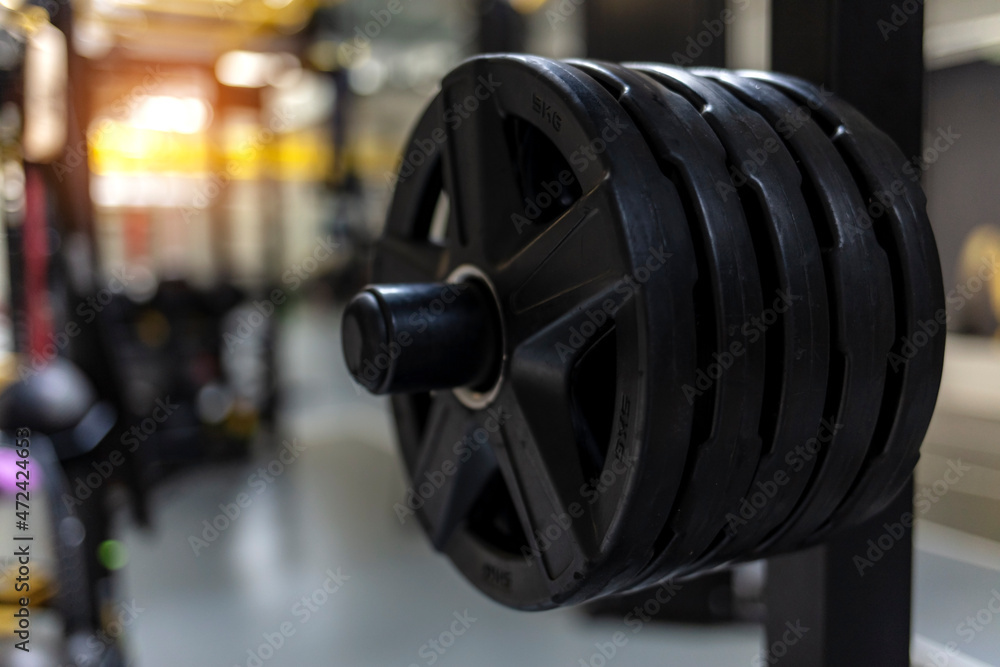 Fototapeta premium Various indoor weight lifting training equipment. Dumbbells in a row at gymnasium or health club interior. Heavy workout equipment designed for cross-training and weight exercise at health club studio
