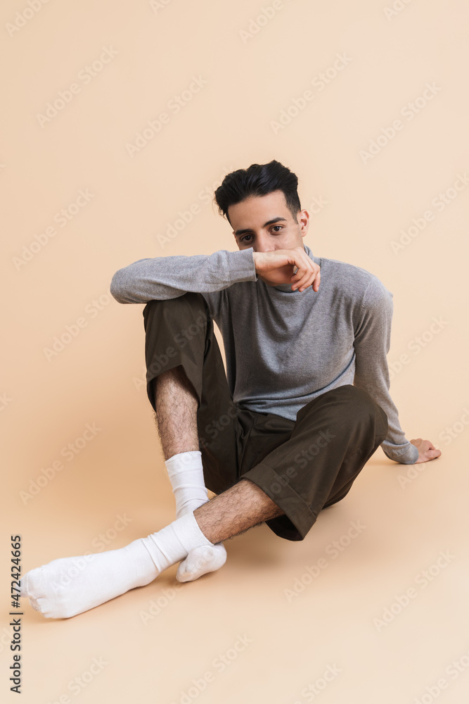 Young middle eastern man looking at camera while sitting on floor