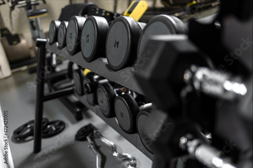 Rows of dumbbells in the gym with sunlight in morning. Sports dumbbells in modern sports club. Weight training equipment. Dumbbell set in sport fitness center room for healthy background concept