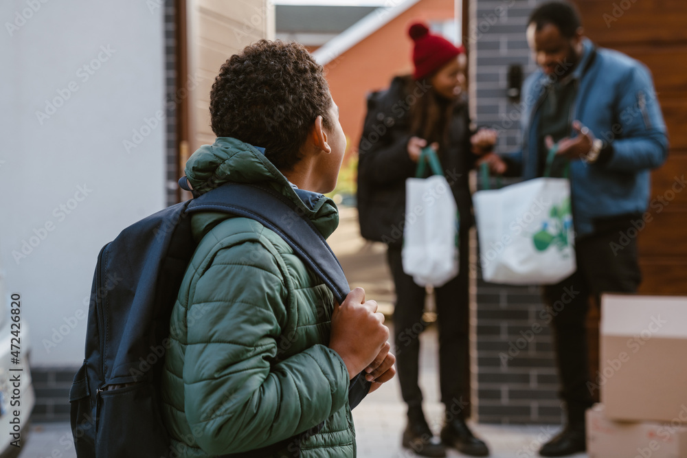Obraz premium Black boy standing on parking during moving with his family
