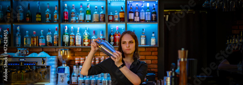 young attractive woman bartender Making Cocktail Using Shaker in bar