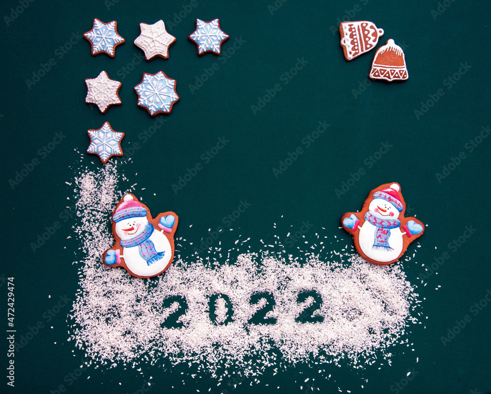 Greeting background with Christmas festive biscuits in the form of snowmen as a symbol of the new year 2022 in the bright New Year illuminations (greeting card, greetings - concept)