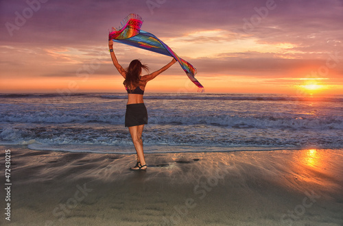 woman dancing in black skirt on the beach at sunset