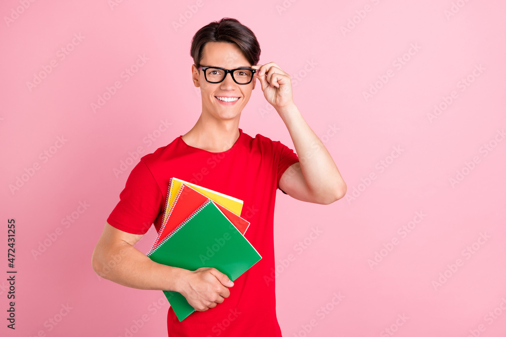 Photo of young guy happy positive smile wear glasses hold notebook study education isolated over pink color background Photo of young guy happy positive smile wear glasses hold notebook study education isolated over pink color background