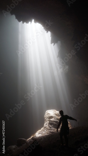 ray of light in grubug cave with silhouette caver, cave jomblang area