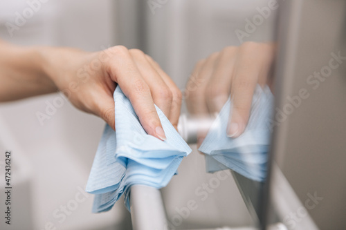 Cleaning glass door handles with an antiseptic wet wipe. Woman hand using towel for cleaning home room door link. Sanitize surfaces prevention in hospital and public spaces against corona virus