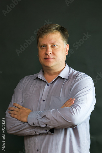 An adult Caucasian man of Slavic appearance in a blue shirt on a black background