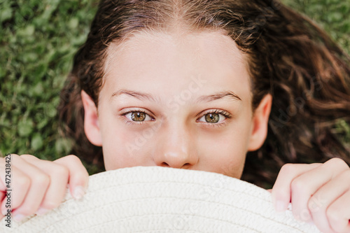 Girl holding hat while lying on grass in summer