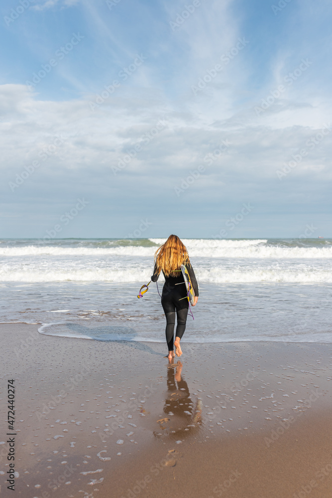 Woman with surfboard walking on wet beach Woman with surfboard walking on wet beach