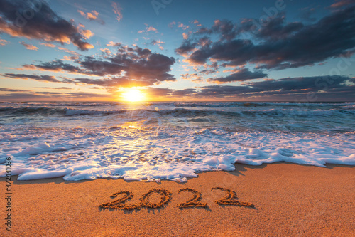 Happy New Year 2022 concept, lettering on the beach. Written text on the sea beach at sunrise. © ValentinValkov
