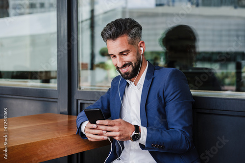 Male entrepreneur using mobile phone while sitting at cafeteria photo