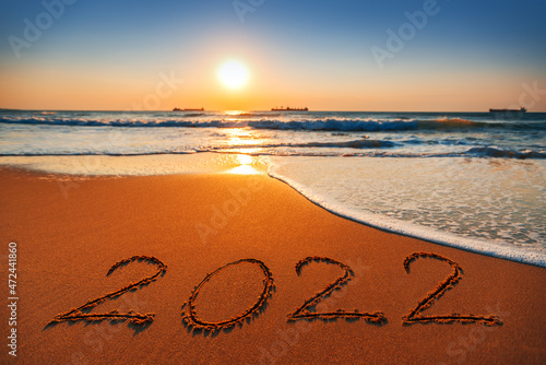 Happy New Year 2022 concept, lettering on the beach. Sea sunrise