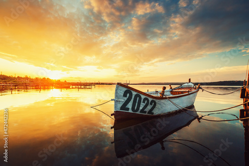 2022 concept Fishing Boat on Varna lake with a reflection in the water at sunset.