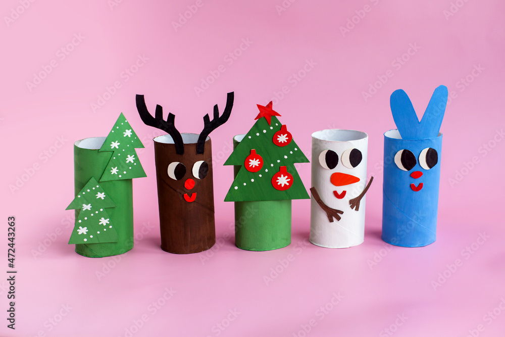 Holiday easy DIY craft idea for kids. Toilet paper roll tube toy Christmas tree, snowman, rabbit, deer on pink background. Creative New Year decoration eco-friendly, reuse, recycle handmade concept
