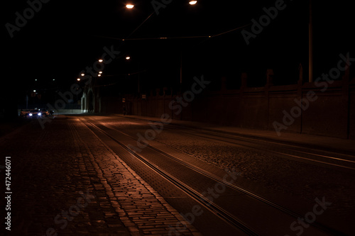 night empty street pavement old European road with background car headlight, soft focus concept photo