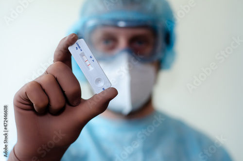Medical laboratory assistant holding positive COVID-19 rapid test.