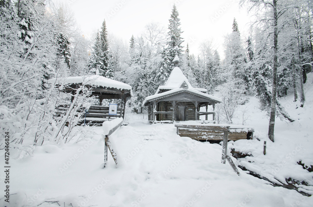 Wooden chapel in a snowy forest. Mineral springs 
