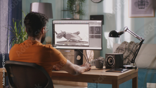 Fotografi Side view of bearded Indian guy using computer to create 3D model of futuristic