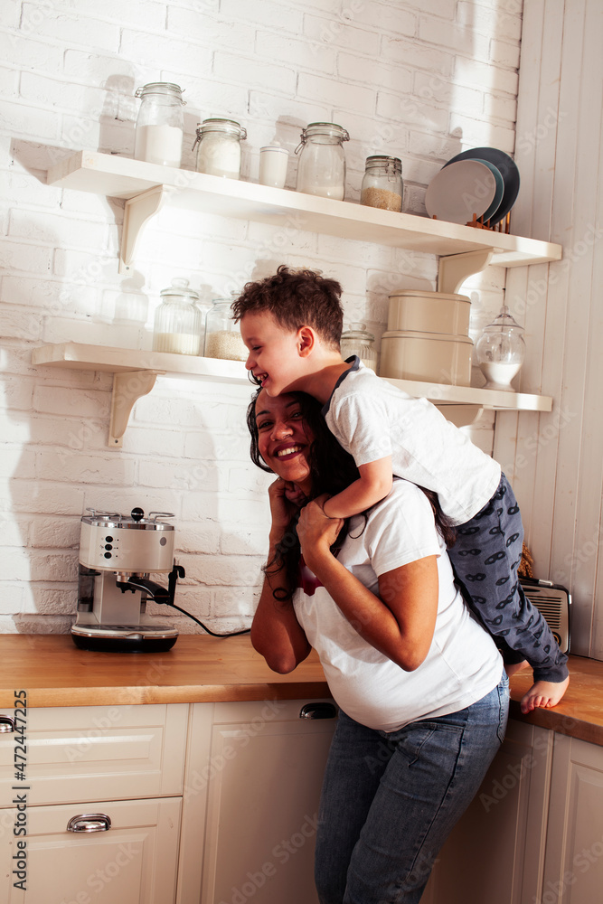 young pretty african american mother with little cute son on kitchen in morning preparing breakfast, lifestyle people concept young pretty african american mother with little cute son on kitchen in morning preparing breakfast, lifestyle people concept