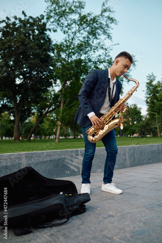Canvas Print Male saxophonist plays melody in park, talent