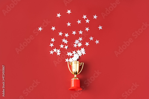 Stars fly out of the gold-colored victory cup on red background
