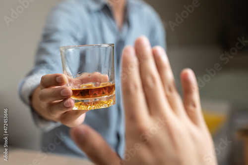 person deny alcohol drink from his friend
