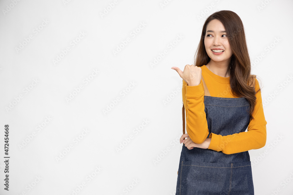 Happy young Asian female housewife wearing kitchen apron cooking and pointing to empty copy space isolated on white background Happy young Asian female housewife wearing kitchen apron cooking and pointing to empty copy space isolated on white background