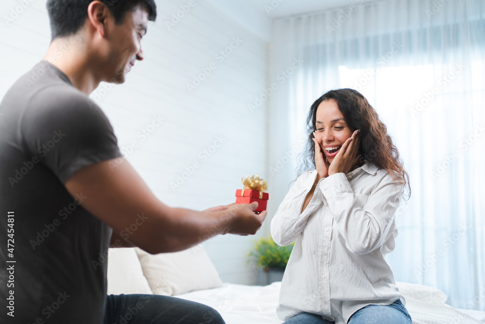 Happy young Hispanic new couple, male surprised the gift to his girlfriend for proposal and celebration Happy young Hispanic new couple, male surprised the gift to his girlfriend for proposal and celebration