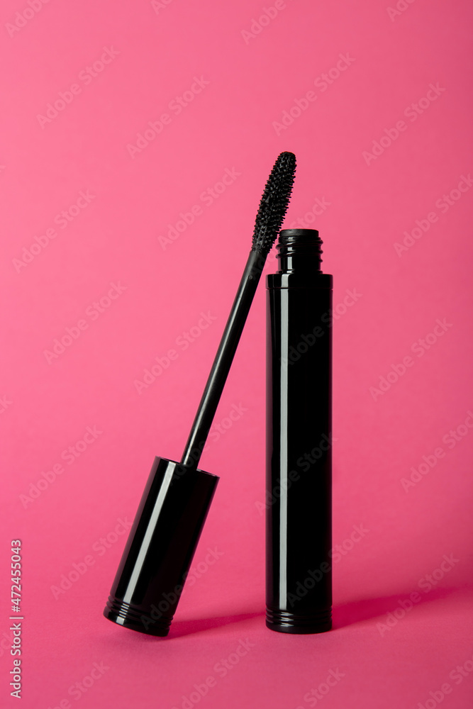 Mascara tube and brush on pink background. Unbranded mascara bottle. Makeup, visage and cosmetology concept Mascara tube and brush on pink background. Unbranded mascara bottle. Makeup, visage and cosmetology concept