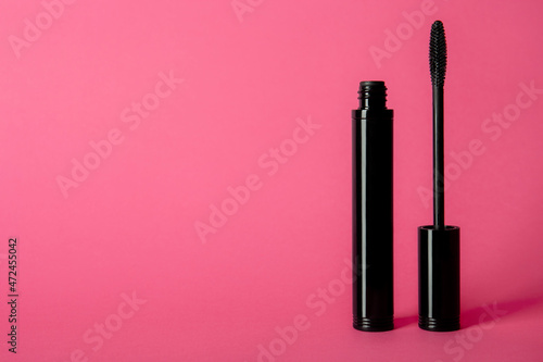 Mascara tube and brush on pink background. Unbranded mascara bottle with place for text. Makeup, visage and cosmetology concept