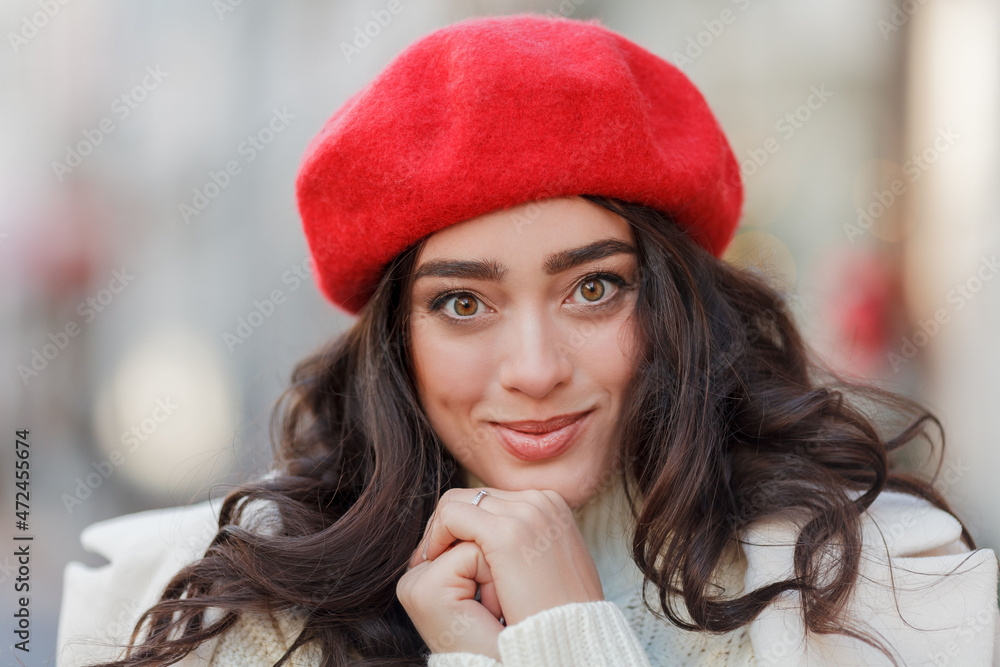 Christmas street style portrait of young beautiful woman in red beret walking in European city for winter holidays. Stylish model with curly hair is doing New Year's shopping. Christmas street style portrait of young beautiful woman in red beret walking in European city for winter holidays. Stylish model with curly hair is doing New Year's shopping.