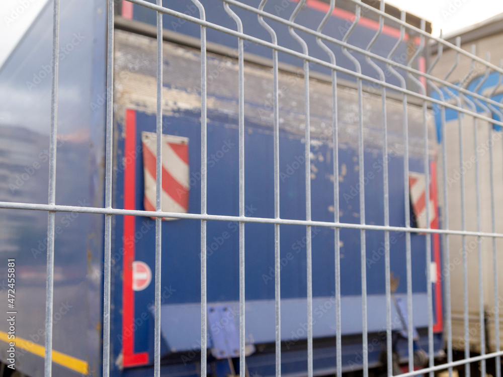 Obraz premium Defocused back view of a metal fence and part of a blue truck.
