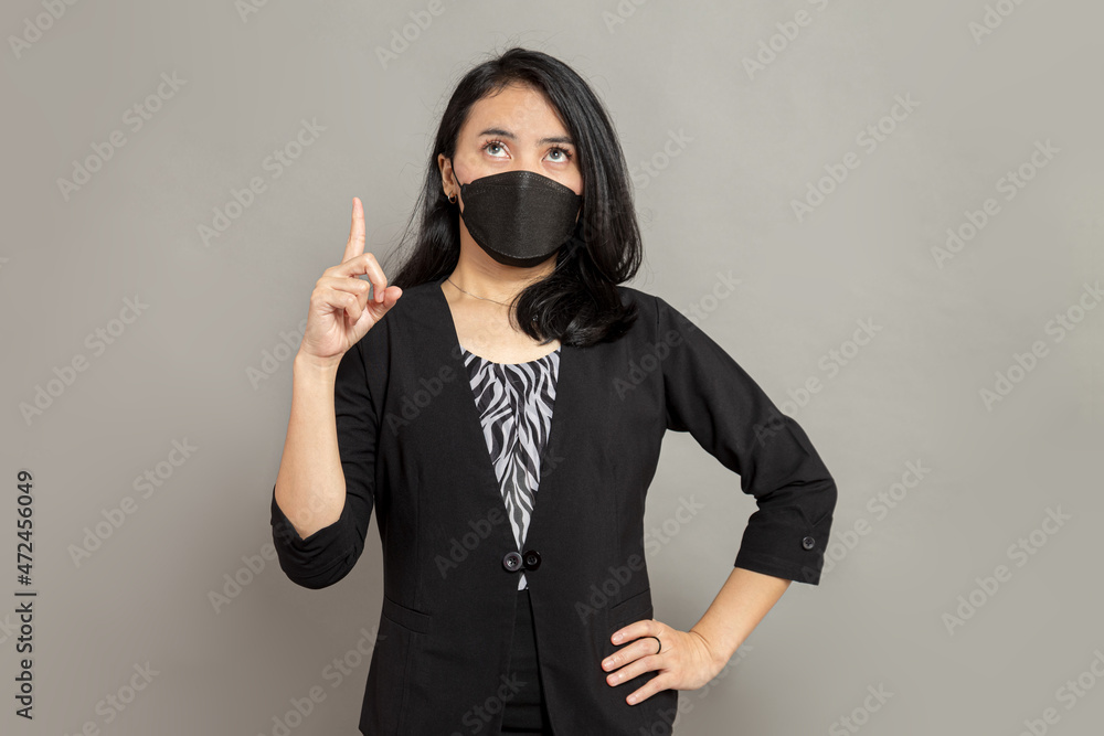 Beautiful woman wearing black mask was looking up and pointing with one hand Beautiful woman wearing black mask was looking up and pointing with one hand