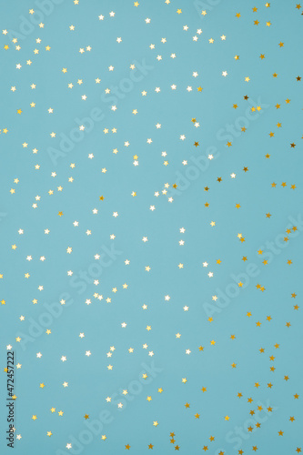 Star shaped shining golden confetti on light blue background. Sparkle sequins. Festive design