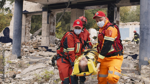 Slika na platnu Tracking shot of multiracial men in paramedic uniform carrying survival and walk