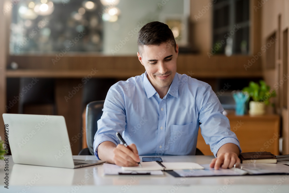Businessman working on laptop and taking notes in office. Businessman working on laptop and taking notes in office.