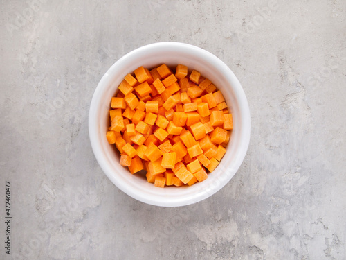 Top view of a white bowl with chopped carrots. Brunoise carrot.