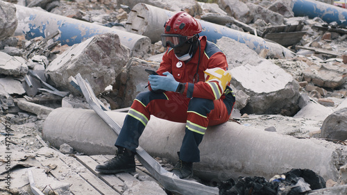 Foto African American man in red uniform sitting on pipe and listening voice message