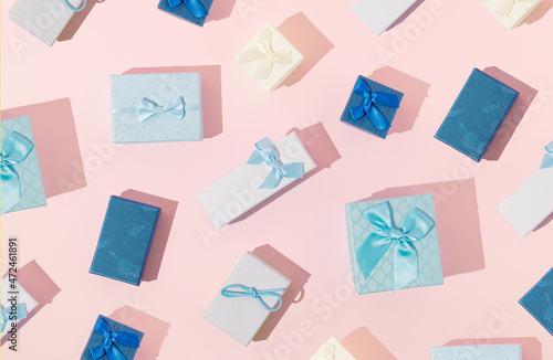 Christmas blue gift boxes pattern on bright background. Creative New Year presents composition. Holidays celebration concept. Flat lay with sunshine shadows.